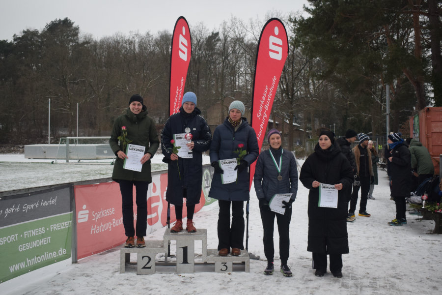 Ein Foto der Siegerehrung der Frauen für die Langstrecke. Die ersten drei stehen auf einem Siegertreppchen, die Plätze vier und fünf rechts daneben.