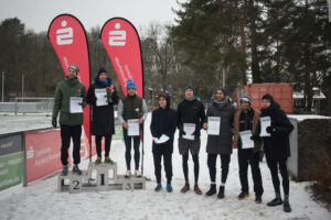 Ein Foto der Siegerehrung der Männer für die Langstrecke. Die ersten drei stehen auf einem Siegertreppchen, die Plätze vier bis acht rechts daneben.