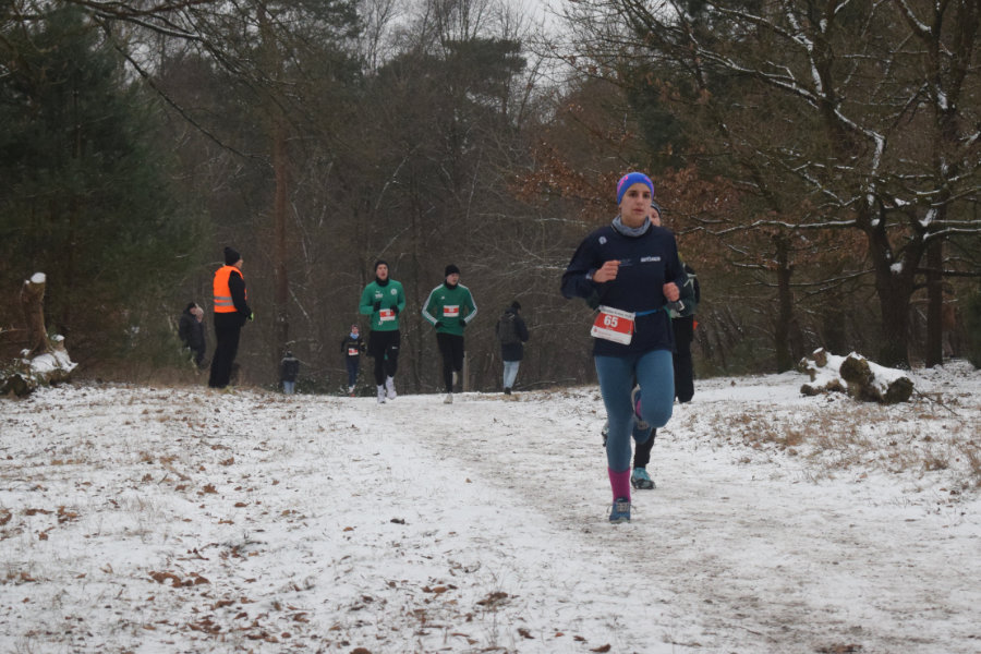Ein Foto von einer Teilnehmerin der Mittelstrecke, im Hintergrund mit etwas Abstand weitere Läufer.