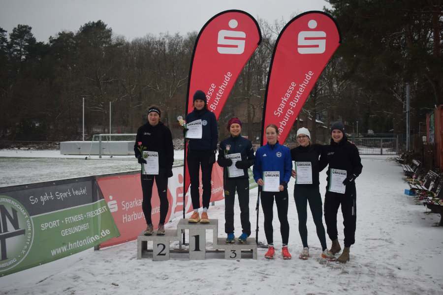 Ein Foto der Siegerehrung der Frauen für die Mittelstrecke. Die ersten drei stehen auf einem Siegertreppchen, die Plätze vier, fünf und sechs rechts daneben.