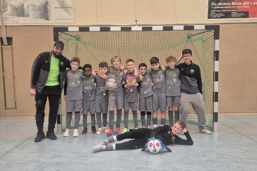 Ein Gruppenfoto der HNT-Mannschaft am Sonntag, auf dem die Spieler in einer Reihe nebeneinander vor einem Tor stehen und Medaillen um den Hals haben.