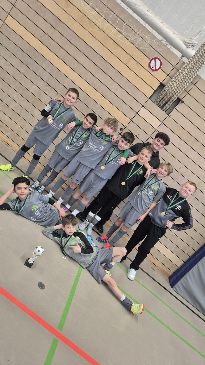 Ein Gruppenfoto von der 1. E-Jugend der HNT beim SVNA-Hallencup, auf dem alle Spieler eine Medaille um den Hals haben; vor ihnen steht der Pokal für den dritten Platz auf dem Boden.