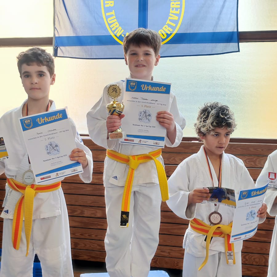 Ein Foto von Nathan auf dem Siegerpodest, er hält stolz einen Pokal und seine Urkunde für den ersten Platz in die Kamera.