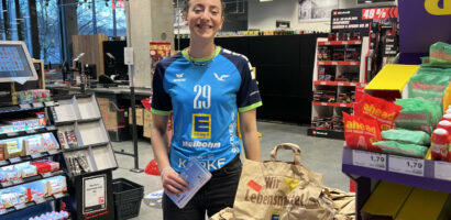 Ein Foto von VTH-Spielerin Sarah Santos Goncalves im Edeka-Markt, neben ihr die vorgepackten Lebensmitteltüten, die gespendet werden konnten.