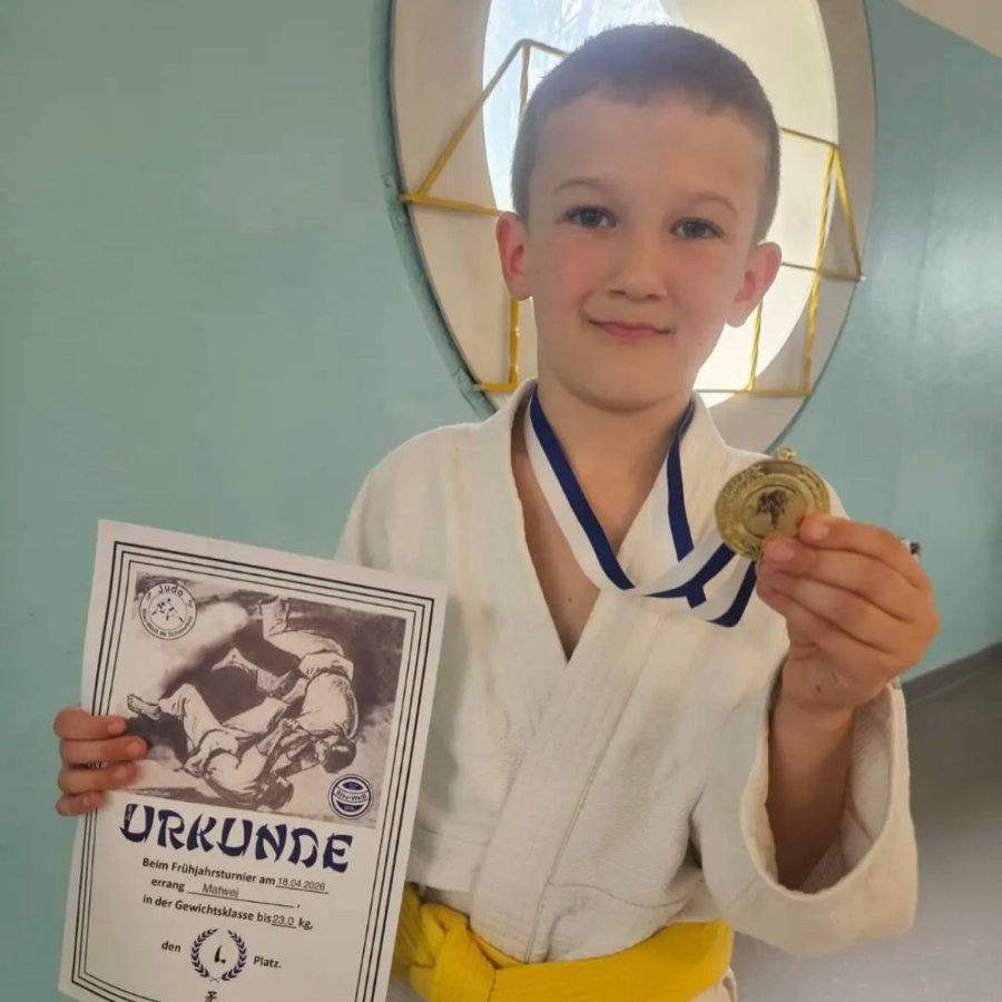 Ein Foto von Matwej, der mit einem Lächeln seine Goldmedaille und seine Urkunde in die Kamera hält.