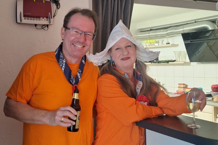 Ein Foto vom Happy-Hours-Event "Gouda Abend", das zwei fröhliche Teilnehmende zeigt, die mit Getränken in den Händen an der Bar stehen.