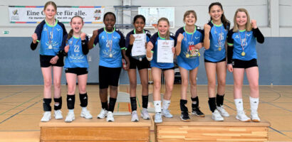 Ein Foto der beiden VTH U12-Teams, die zusammen auf dem Siegerpodest stehen und in die Kamera jubeln.