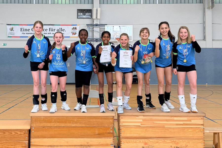 Ein Foto der beiden VTH U12-Teams, die zusammen auf dem Siegerpodest stehen und in die Kamera jubeln.