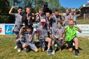 Ein Gruppenfoto der 1. E-Jugend der HNT, auf dem die Kinder in die Kamera jubeln.
