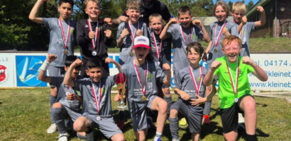 Ein Gruppenfoto der 1. E-Jugend der HNT, auf dem die Kinder in die Kamera jubeln.