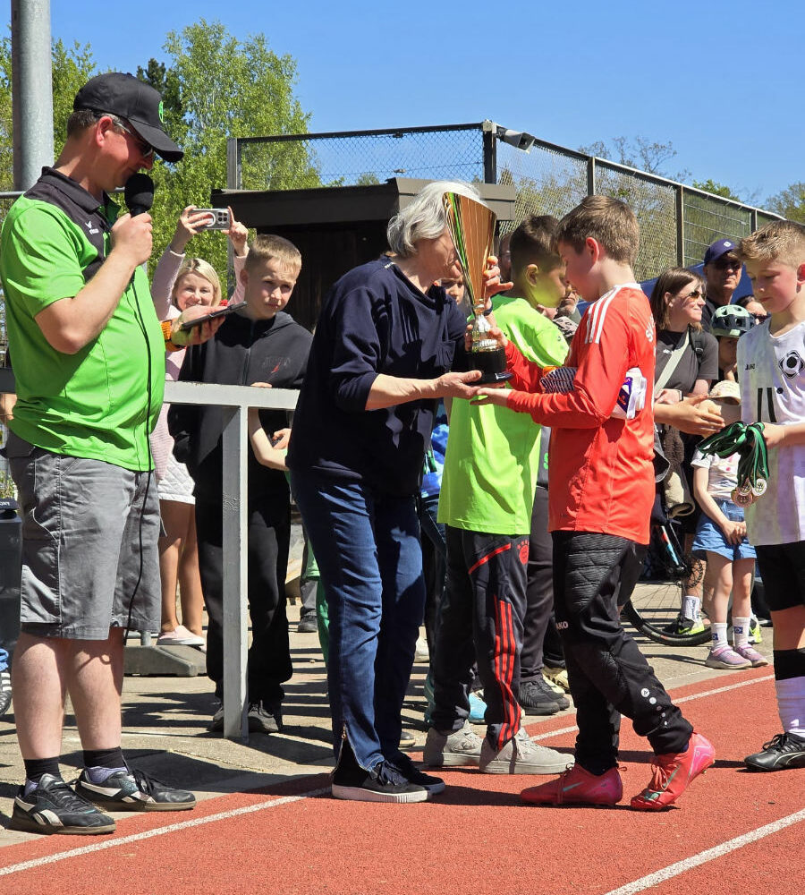 Ein Foto von der Siegerehrung, auf dem Lydia Fischer einem Spieler einen Pokal überreicht.