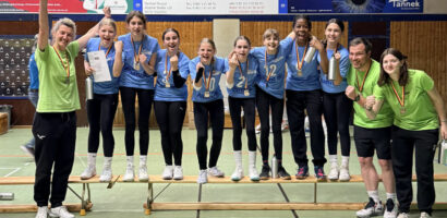 Ein Foto von der Siegerehrung, auf dem die U14-Spielerinnen des VTH nebeneinander auf einer Bank stehen und mit Medaillen um den Hälsen in die Kamera jubeln.