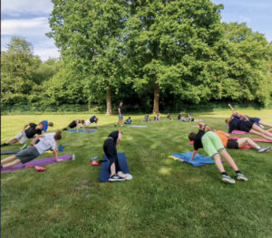 Ein Foto von der HNT-Trainingsgruppe beim Stretching auf einer Wiese.