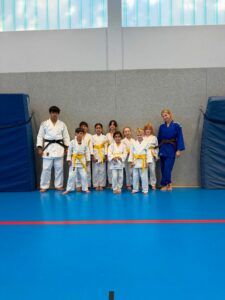 Ein Gruppenfoto in der Sporthalle von den jungen Judoka mit ihren Prüfern Briana und Brian.