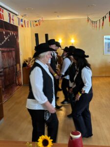 Ein Foto von mehreren Mitgliedern der Jolly Boots, die in zwei Reihen nebeneinander tanzen.