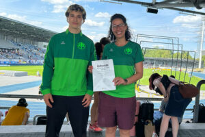 Ein Foto von Nils Hofmann zusammen mit Trainerin Houssaina Dridi, die seine Urkunde in die Kamera hält, im Hintergrund das Stadion in Bochum-Wattenscheid.