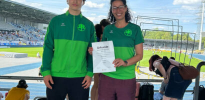 Ein Foto von Nils Hofmann zusammen mit Trainerin Houssaina Dridi, die seine Urkunde in die Kamera hält, im Hintergrund das Stadion in Bochum-Wattenscheid.
