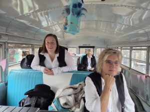 Ein Foto von Mitgliedern der Jolly Boots, die in einem alten Schulbus sitzen, der auf dem Landhof steht.
