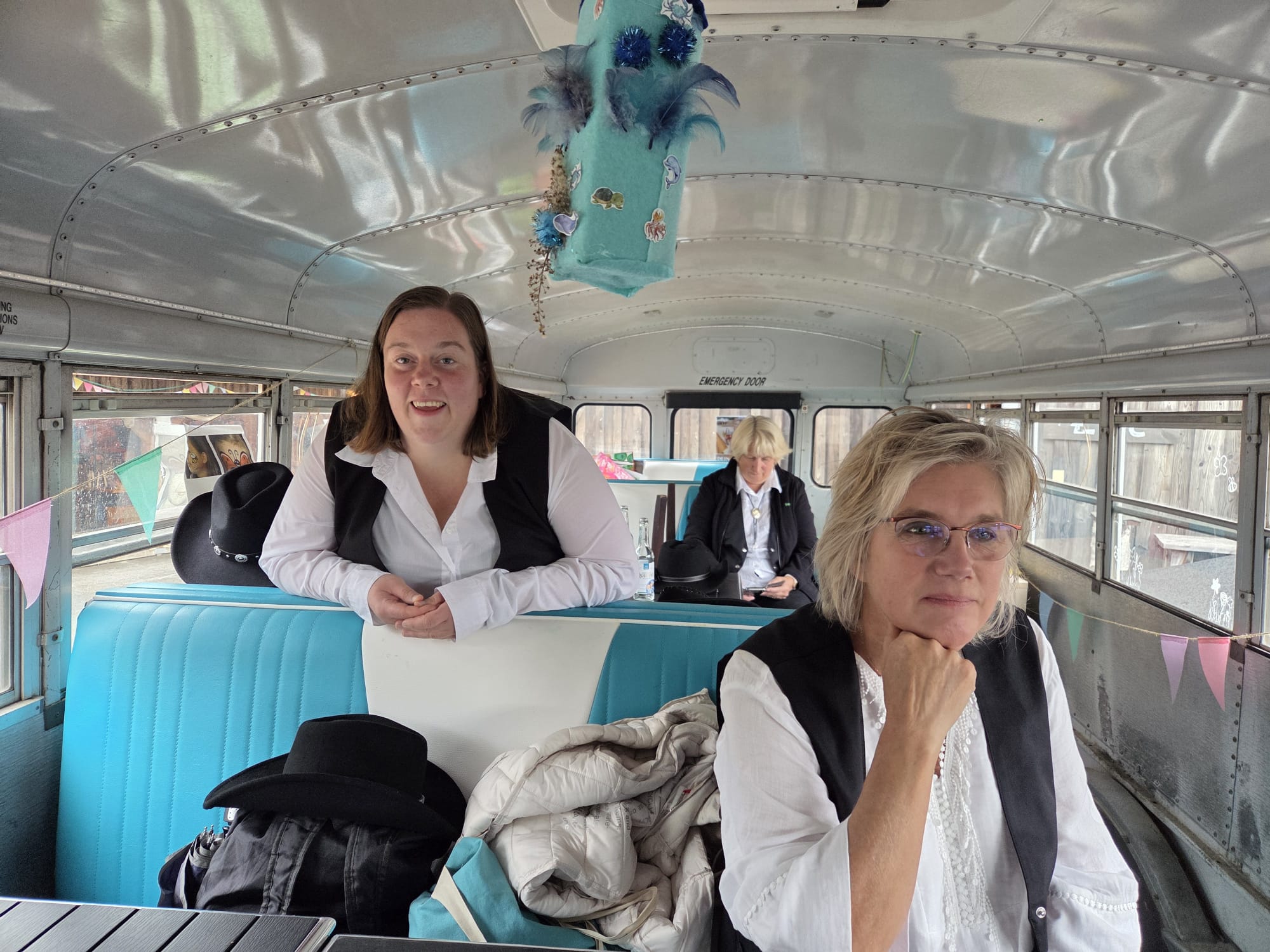 Ein Foto von Mitgliedern der Jolly Boots, die in einem alten Schulbus sitzen, der auf dem Landhof steht.