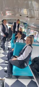 Ein Foto von Mitgliedern der Jolly Boots, die in einem alten Schulbus sitzen, der auf dem Landhof steht.