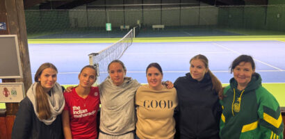 Ein Foto des HNT Damen-Teams, auf dem die Spielerinnen eng nebeneinander mit um die Schultern gelegten Armen vor dem Tennisplatz stehen.
