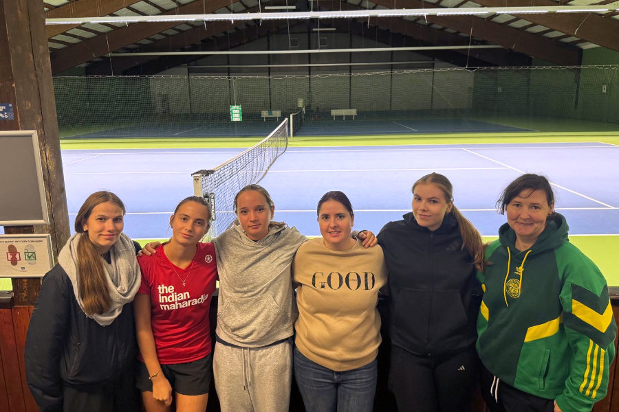 Ein Foto des HNT Damen-Teams, auf dem die Spielerinnen eng nebeneinander mit um die Schultern gelegten Armen vor dem Tennisplatz stehen.