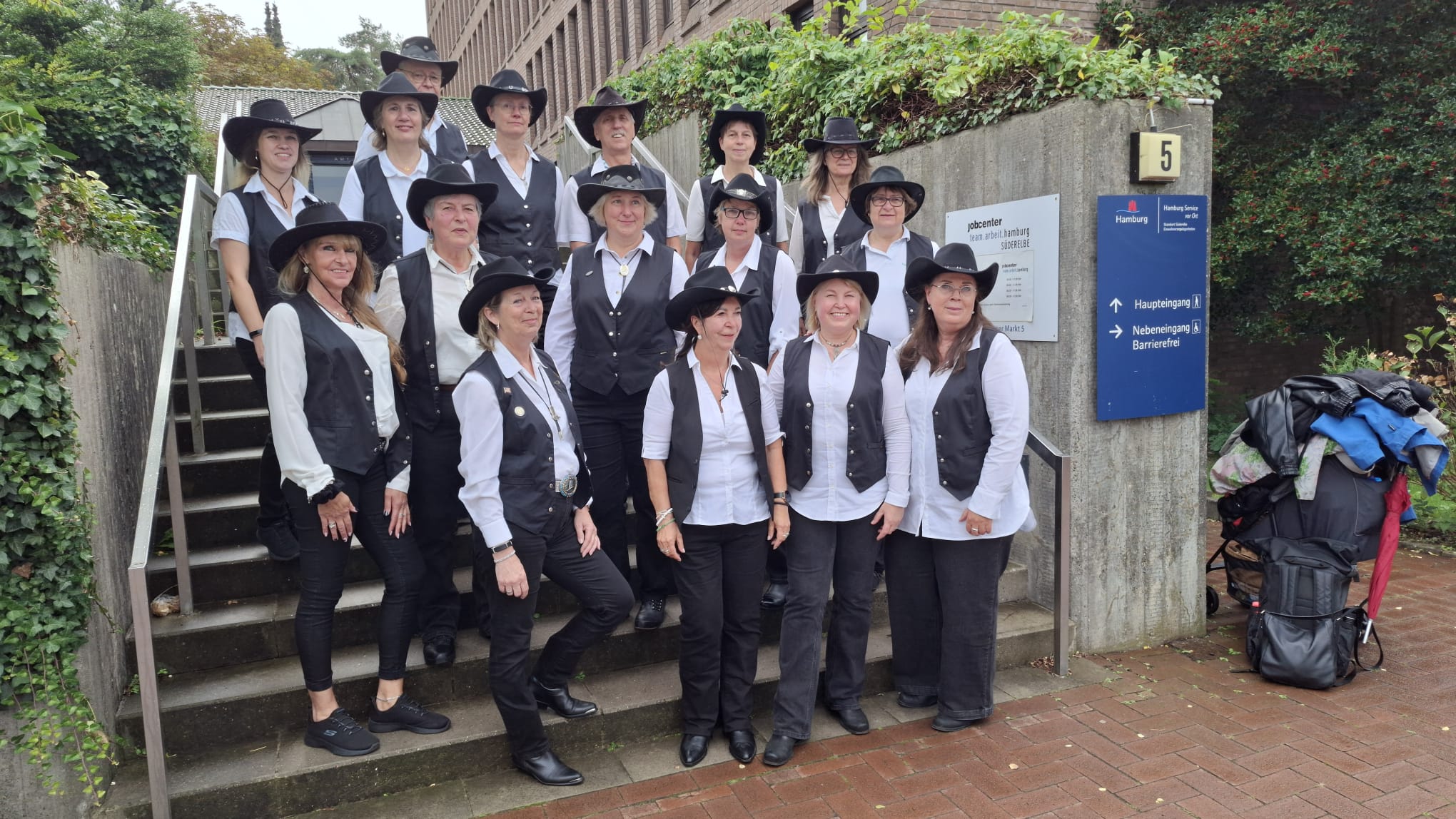 Ein Gruppenfoto der Jolly Boots, auf dem sich die Mitglieder auf einer Treppe auf mehreren Stufen verteilt aufgestellt haben.