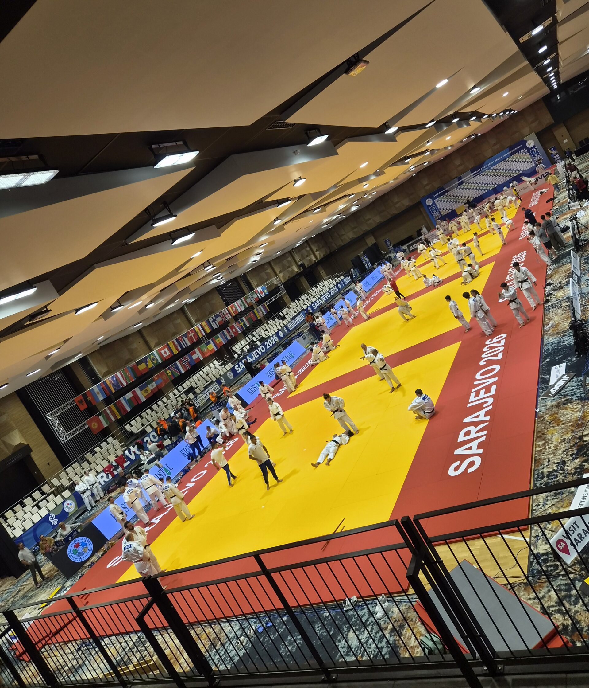 Ein Foto aus dem Inneren der Wettkampfhalle, in der auf mehreren Matten gleichzeitig Judokämpfe stattfinden.